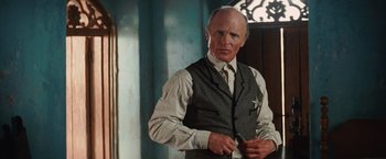 Movie still from “Appaloosa” (2008), directed by Ed Harris – An older man in a vest and tie holding a knife; Medium shot, Low angle