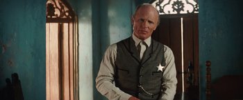 Movie still from “Appaloosa” (2008), directed by Ed Harris – An older man in a suit and tie; Medium shot, Low angle