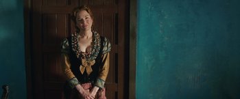 Movie still from “Appaloosa” (2008), directed by Ed Harris – A woman standing in front of a door wearing a dress; Medium shot, Over the shoulder angle