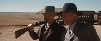 Movie still from “Appaloosa” (2008), directed by Ed Harris – Two men in suits and hats are holding guns; Medium shot, Over the shoulder angle