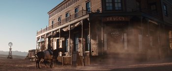 Movie still from “Appaloosa” (2008), directed by Ed Harris – A man riding a horse in front of a building; Wide shot, Low angle