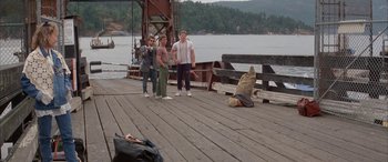 Movie still from “April Fool's Day” (1986), directed by Fred Walton – Two people standing on a dock with a dog; Wide shot, High angle