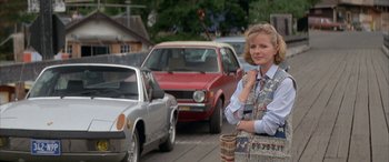 Movie still from “April Fool's Day” (1986), directed by Fred Walton – A woman standing on the side of a road next to cars; Medium shot, Low angle