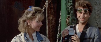 Movie still from “April Fool's Day” (1986), directed by Fred Walton – A woman is smiling while looking at a cell phone; Close Up shot, Over the shoulder angle