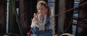 Movie still from “April Fool's Day” (1986), directed by Fred Walton – A woman sitting in a chair holding a cell phone; Close Up shot, Low angle