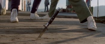 Movie still from “April Fool's Day” (1986), directed by Fred Walton – A knife that is on the ground in front of some people; Extreme Close Up shot, High angle