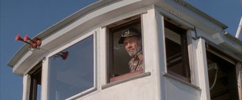Movie still from “April Fool's Day” (1986), directed by Fred Walton – An older man wearing a hat looking out of a window; Medium shot, Low angle
