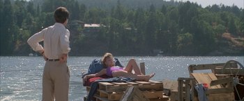 Movie still from “April Fool's Day” (1986), directed by Fred Walton – A girl laying on a pile of wood in the middle of a lake; Wide shot, High angle
