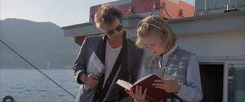 Movie still from “April Fool's Day” (1986), directed by Fred Walton – A man and a woman are looking at a book; Medium shot, Low angle