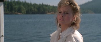 Movie still from “April Fool's Day” (1986), directed by Fred Walton – A woman in a white dress standing in front of a body of water; Close Up shot, Low angle