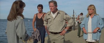 Movie still from “April Fool's Day” (1986), directed by Fred Walton – A man and a woman standing next to a body of water; Medium shot, Low angle