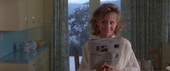 Movie still from “April Fool's Day” (1986), directed by Fred Walton – A woman holding a newspaper in front of a window; Close Up shot, Over the shoulder angle