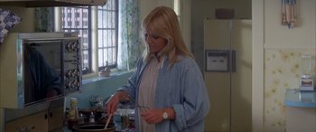 Movie still from “April Fool's Day” (1986), directed by Fred Walton – A woman in a blue shirt is cooking in a kitchen; Medium shot, High angle