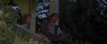 Movie still from “April Fool's Day” (1986), directed by Fred Walton – A man sitting on a porch holding a glass of wine; Medium shot, Low angle