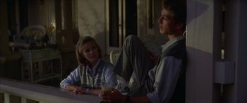 Movie still from “April Fool's Day” (1986), directed by Fred Walton – A man and a woman sitting at a table with a drink; Medium shot, Over the shoulder angle