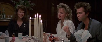 Movie still from “April Fool's Day” (1986), directed by Fred Walton – A woman sitting in front of a table with candles and figurines on it; Medium shot, High angle