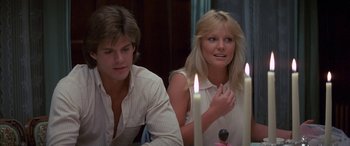 Movie still from “April Fool's Day” (1986), directed by Fred Walton – A man and a woman sitting at a table with candles in front of them; Close Up shot, Over the shoulder angle