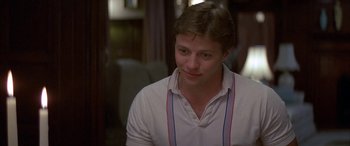 Movie still from “April Fool's Day” (1986), directed by Fred Walton – A young man in a white shirt is looking at the camera; Close Up shot, Over the shoulder angle