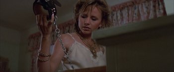 Movie still from “April Fool's Day” (1986), directed by Fred Walton – A woman in a white top holding a hair dryer; Close Up shot, Low angle