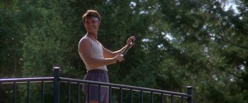 Movie still from “April Fool's Day” (1986), directed by Fred Walton – A man holding a tennis racquet on top of a railing; Medium shot, Low angle