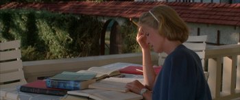 Movie still from “April Fool's Day” (1986), directed by Fred Walton – A woman sitting at a table reading a book; Medium shot, High angle
