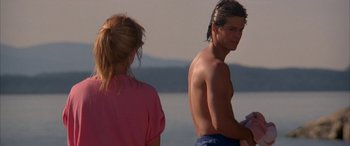 Movie still from “April Fool's Day” (1986), directed by Fred Walton – A man and a woman standing next to each other on the beach; Medium shot, Over the shoulder angle