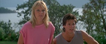 Movie still from “April Fool's Day” (1986), directed by Fred Walton – A woman and a man standing next to each other in front of trees; Close Up shot, Low angle