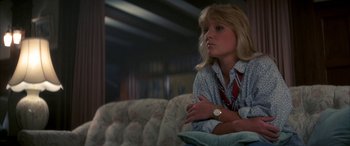 Movie still from “April Fool's Day” (1986), directed by Fred Walton – A woman sitting on top of a couch in front of a window; Close Up shot, Low angle