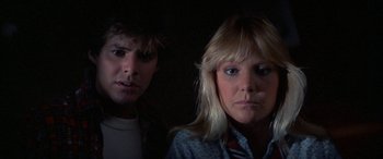 Movie still from “April Fool's Day” (1986), directed by Fred Walton – A man and a woman looking at the camera in a dark room; Close Up shot, Low angle