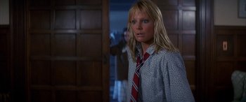 Movie still from “April Fool's Day” (1986), directed by Fred Walton – A woman in a red and white striped neck tie standing in front of a door; Medium shot, Low angle