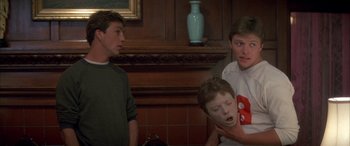 Movie still from “April Fool's Day” (1986), directed by Fred Walton – Three young men standing in front of a fireplace; Close Up shot, Over the shoulder angle