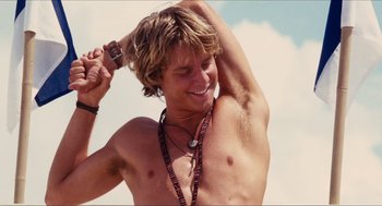 Movie still from “Aquamarine” (2006), directed by Elizabeth Allen Rosenbaum – A shirtless man with a camera around his neck; Close Up shot, Low angle