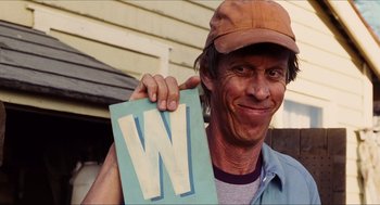 Movie still from “Aquamarine” (2006), directed by Elizabeth Allen Rosenbaum – A man holding up a letter w in front of his face; Close Up shot, Low angle