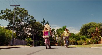 Movie still from “Aquamarine” (2006), directed by Elizabeth Allen Rosenbaum – Two kids riding scooters down a street with palm trees in the background; Extreme Wide shot, Low angle