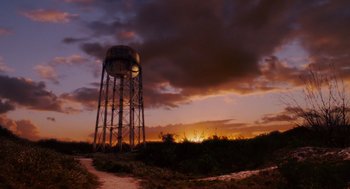 Movie still from “Aquamarine” (2006), directed by Elizabeth Allen Rosenbaum – The sun sets behind a water tower on a cloudy day; Extreme Wide shot, Low angle