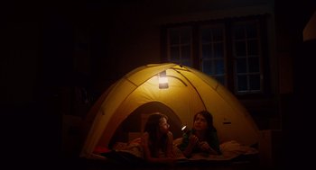 Movie still from “Aquamarine” (2006), directed by Elizabeth Allen Rosenbaum – Two young girls sitting under a tent in the dark; Wide shot, Low angle