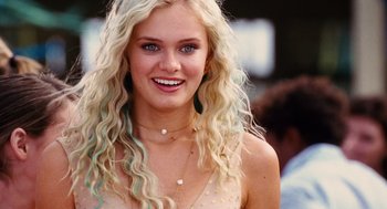 Movie still from “Aquamarine” (2006), directed by Elizabeth Allen Rosenbaum – A woman with blonde hair and blue eyes smiling for the camera; Close Up shot, Over the shoulder angle