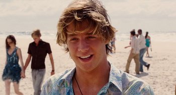 Movie still from “Aquamarine” (2006), directed by Elizabeth Allen Rosenbaum – A young man is smiling on the beach; Close Up shot, Over the shoulder angle