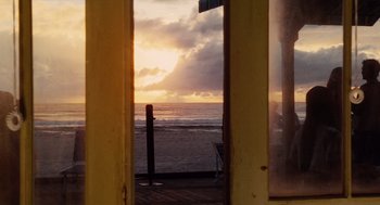 Movie still from “Aquamarine” (2006), directed by Elizabeth Allen Rosenbaum – The sun is setting over the ocean as seen through a window; Wide shot, Over the shoulder angle