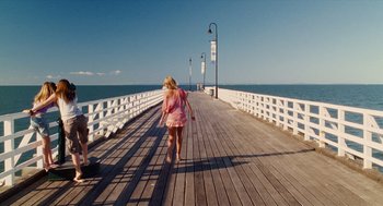 Movie still from “Aquamarine” (2006), directed by Elizabeth Allen Rosenbaum – A woman in a pink dress is walking on a pier; Extreme Wide shot, High angle