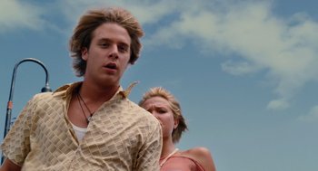 Movie still from “Aquamarine” (2006), directed by Elizabeth Allen Rosenbaum – A man and a woman standing next to each other in front of a sky background; Close Up shot, Low angle