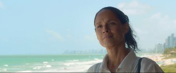 An older woman standing in front of the ocean