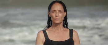 An older woman with wet hair standing on the beach