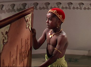 Movie still from “Arabian Nights” (1942), directed by John Rawlins – A young man wearing a red hat is writing on a board; Medium shot, High angle