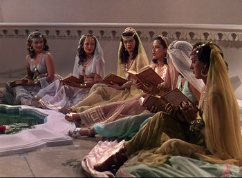 Movie still from “Arabian Nights” (1942), directed by John Rawlins – A group of women sitting on the ground reading books; Wide shot, High angle