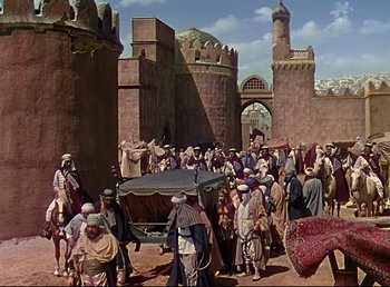 Movie still from “Arabian Nights” (1942), directed by John Rawlins – A painting of a group of people gathered around a car; Extreme Wide shot, High angle