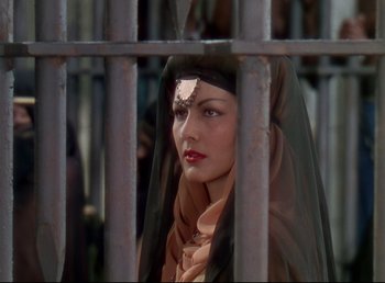 Movie still from “Arabian Nights” (1942), directed by John Rawlins – A woman with a veil on her head looking through a metal fence; Close Up shot, Low angle