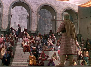 Movie still from “Arabian Nights” (1942), directed by John Rawlins – A group of people sitting on some steps; Extreme Wide shot, High angle