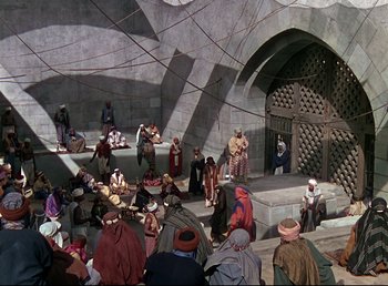 Movie still from “Arabian Nights” (1942), directed by John Rawlins – A group of people sitting on steps in front of a building; Extreme Wide shot, High angle