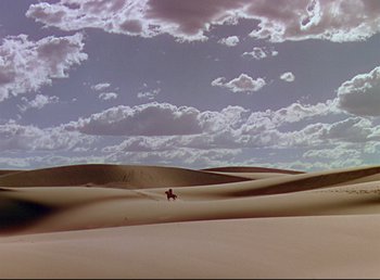 Movie still from “Arabian Nights” (1942), directed by John Rawlins – A person riding a horse on top of a sand dune; Extreme Wide shot, High angle